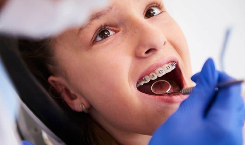 Young patient with metal braces receiving orthodontic examination from dentist in Englewood, CO.