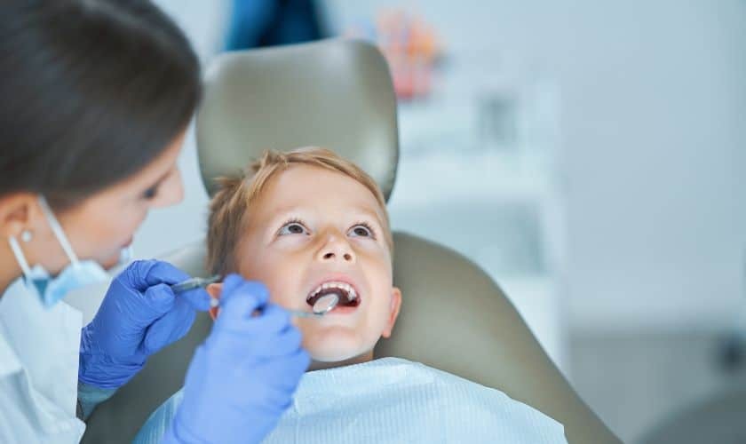 Young boy receiving dental examination in chair from pediatric dentist in Englewood.