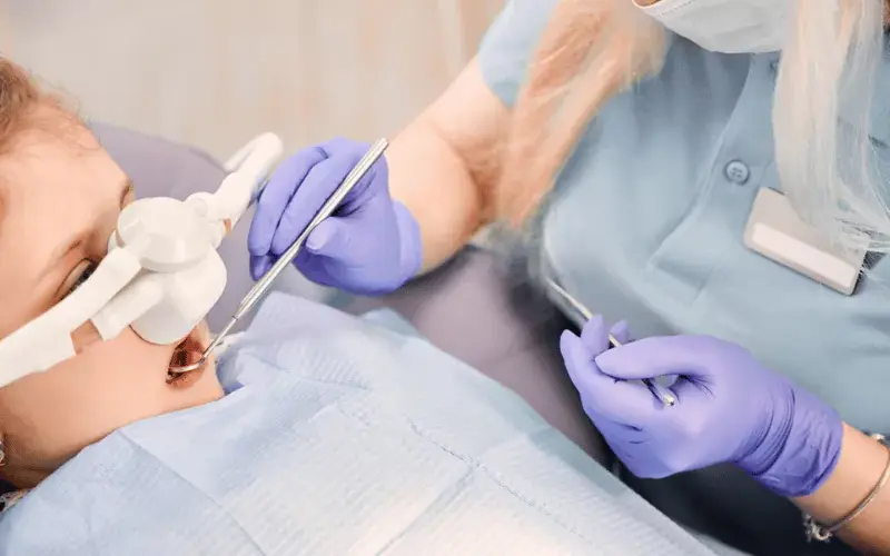 Pediatric dentist performing oral conscious sedation procedure on young patient in Englewood, CO.