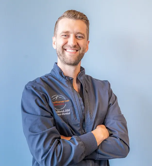 Dr. Lane Bland, DDS, smiling dentist in blue scrubs at Englewood dental practice.