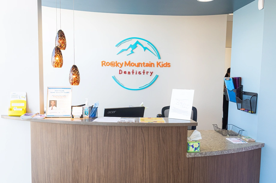 Rocky Mountain Kids Dentistry reception desk with blue logo, wooden counter, and waiting area.