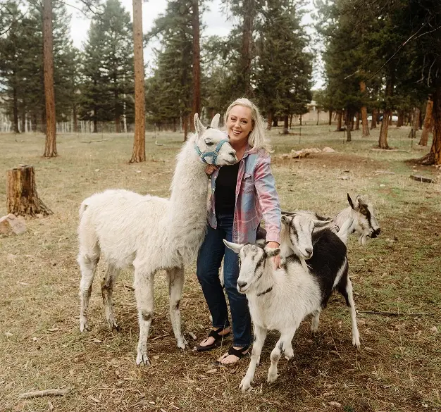 Dr. Heather Jenkins with llamas in a forest setting in Englewood, Colorado.