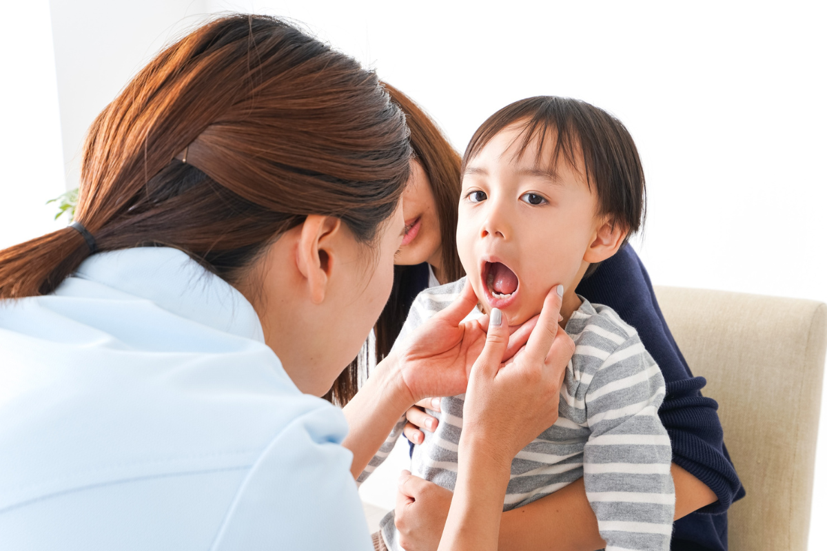 Pediatric dentist examining young child's mouth during dental checkup.
